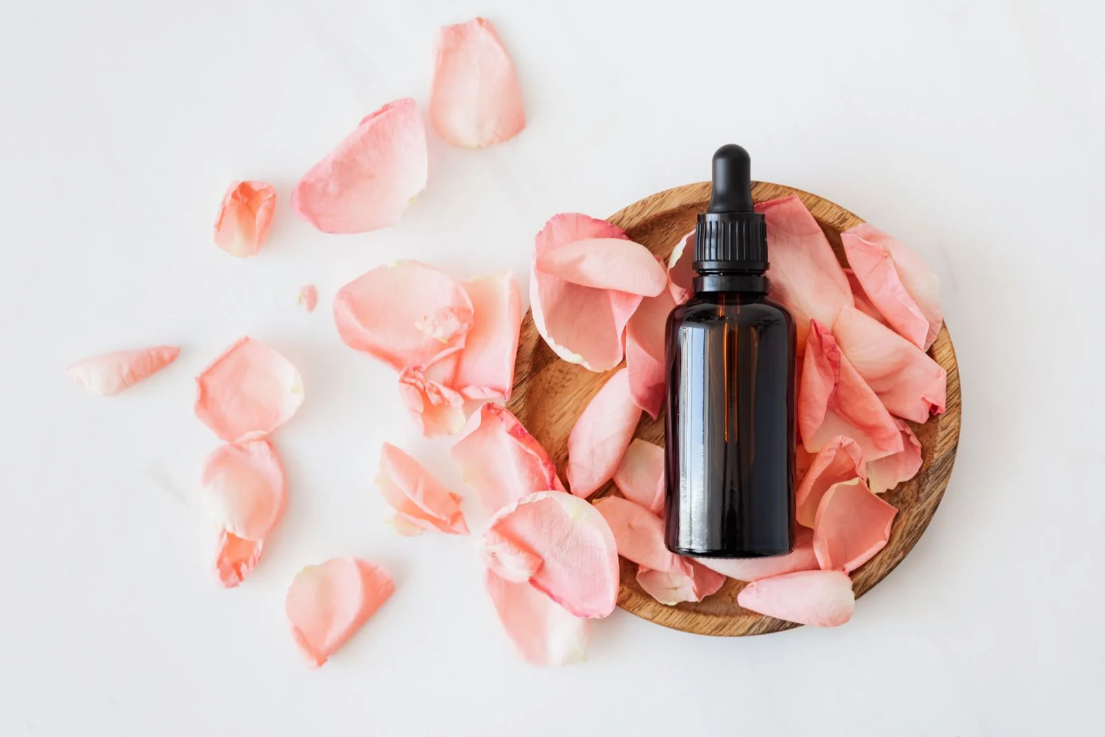 Flacon goutte et pétales de rose sur marbre